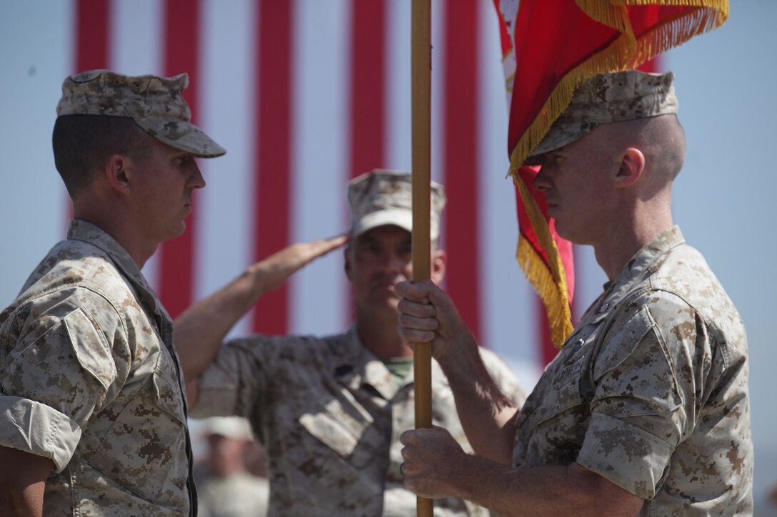 Lieutenant Col. Brian Russell, the outgoing commanding officer of 1st Air Naval Gunfire Liaison Company, prepares to turn over the company colors to the incoming commanding officer, Lt. Col. Jonathan Sims, at a change of command ceremony aboard Marine Corps Base Camp Pendleton, Calif., June 18, 2015.