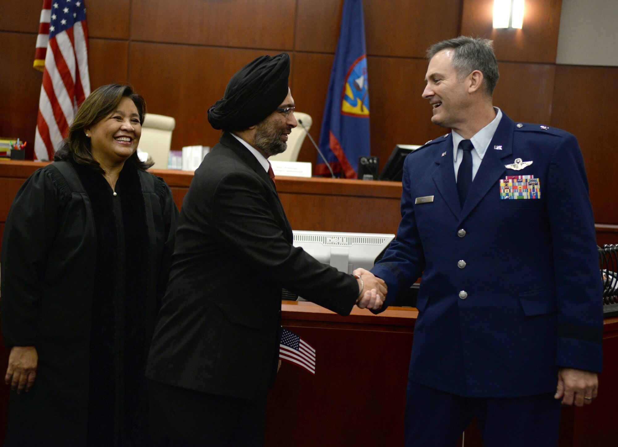 Brig. Gen. Andrew Toth, 36th Wing commander, right, congratulates Hargopal Sachdev, center, on his naturalization as U.S. citizen July 2, 2015, in Hagåtña, Guam. Toth welcomed 24 new citizens as Americans and encouraged them to value their individual heritage as they embrace their new home. (U.S. Air Force photo by Senior Airman Alexander W. Riedel/Released)