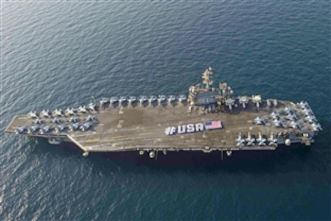 Sailors spell out #USA next to the American flag to mark Independence Day on the flight deck of the aircraft carrier USS Theodore Roosevelt in the Arabian Sea, June 28, 2015. The carrier is deployed to the U.S. 5th Fleet area of operations to support Operation Inherent Resolve and strike operations in Iraq and Syria.