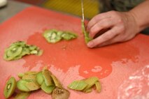 A culinary specialist chops kiwis during the Warrior Chef Challenge June 30, 2015, at Malmstrom Air Force Base, Mont. Kiwi was the secret ingredient that the five teams had to incorporate into their presentations, either in the main entree or in a side dish. U.S. Air Force photo/Chris Willis)