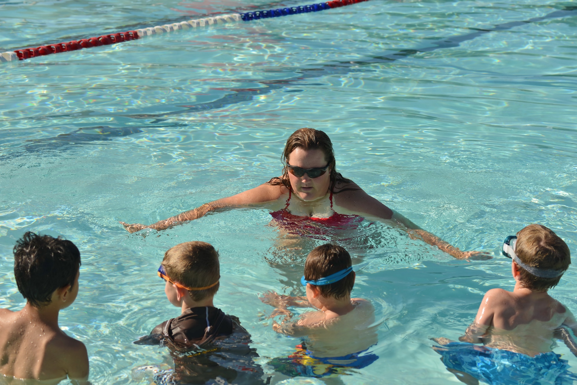 Leanne Hancock, left, teaches a swimming lesson at the base pool to a group of children. Beginning July 13, there will be morning and evening sessions for a variety of age ranges, from parent and tot sessions to advanced. The lessons are sponsored by Outdoor Recreation. (Photo by Jamie Burnett)