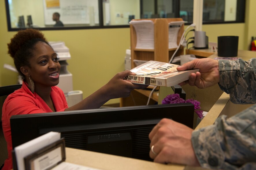 U.S. Air Force Tech. Sgt. Jonathan Falks, 23d Civil Engineer Squadron heavy equipment operator, checks out a book from LaVon Washington, 23d Force Support Squadron customer service representative, in the library July 1, 2015, at Moody Air Force Base, Ga. The Information Learning Center is re-opening the library July 8 after being closed for nearly two years. (U.S. Air Force photo by Airman 1st Class Kathleen D. Bryant)
