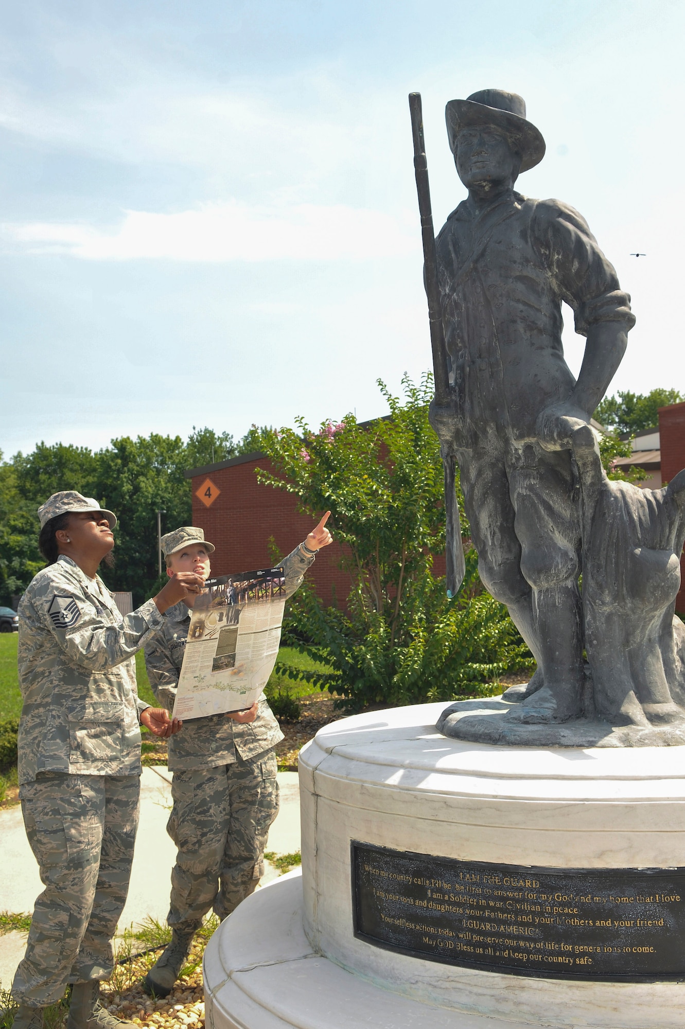 From right, Airman Samantha Grabowski and Master Sgt. Kathy Robinson, both members of the Air National Guard, refer to a brochure from the Minute Man National Historic Park as they look at the replica statue in front of the 116th Air Control Wing headquarters building. (U.S. Air Force photo by Misuzu Allen)