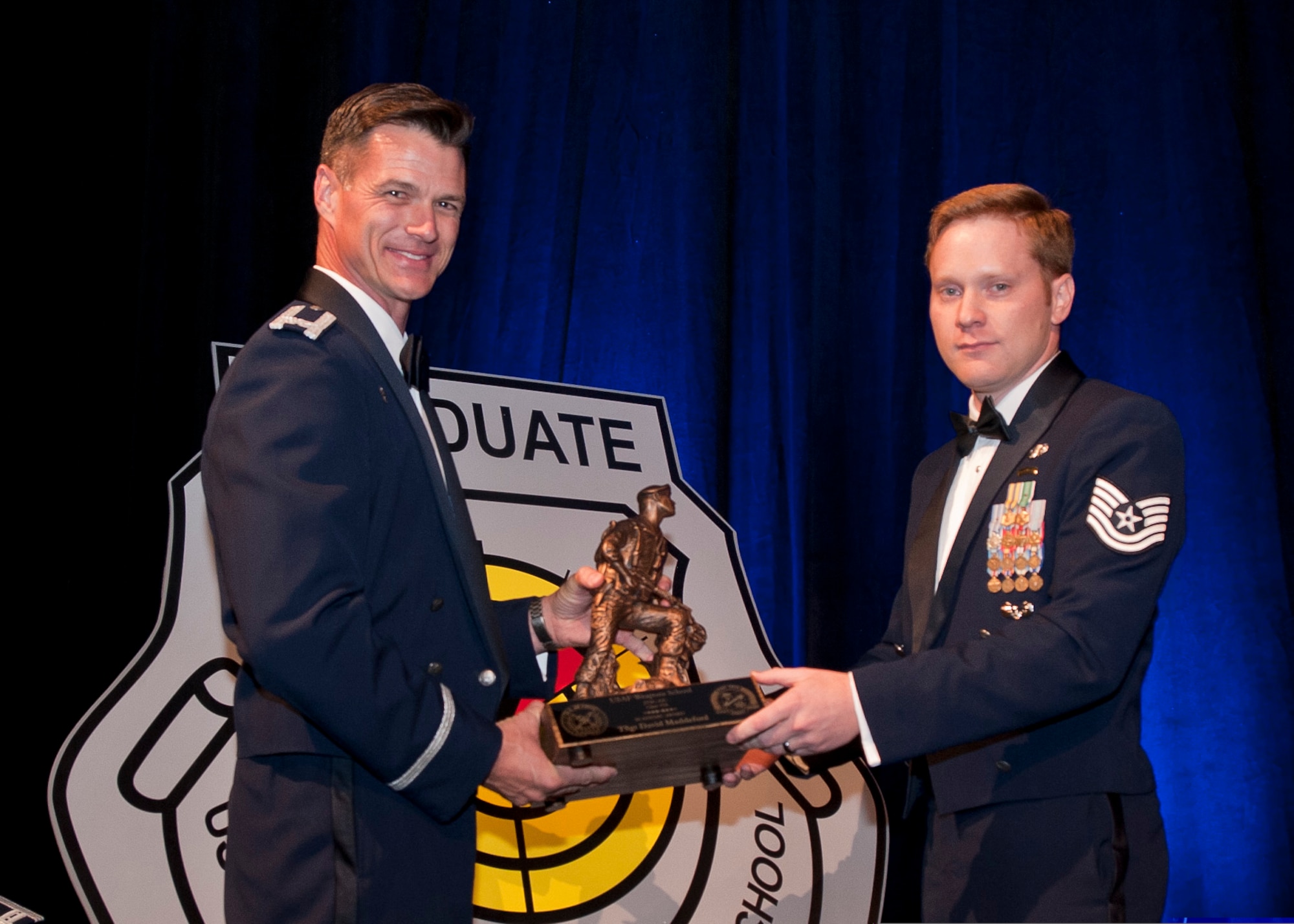 After graduating from U.S. Air Force Weapons School, Tech. Sgt. David Maddeford receives Top Graduate and Outstanding Graduate awards from Col. Michael Drowley, Commandant, for USAF Weapons School, during a graduation ceremony held June 27, 2015, in Las Vegas, Nev. Maddeford, Joint Terminal Attack Controller (JTAC) with the 118th Air Support Operations Squadron, New London, N.C., joined four other graduates as the first and only enlisted in the school’s 66-year history, to also be awarded the coveted graduate patch. (U.S. Air Force photo by Senior Airman Joshua Kleinholz/Released) 