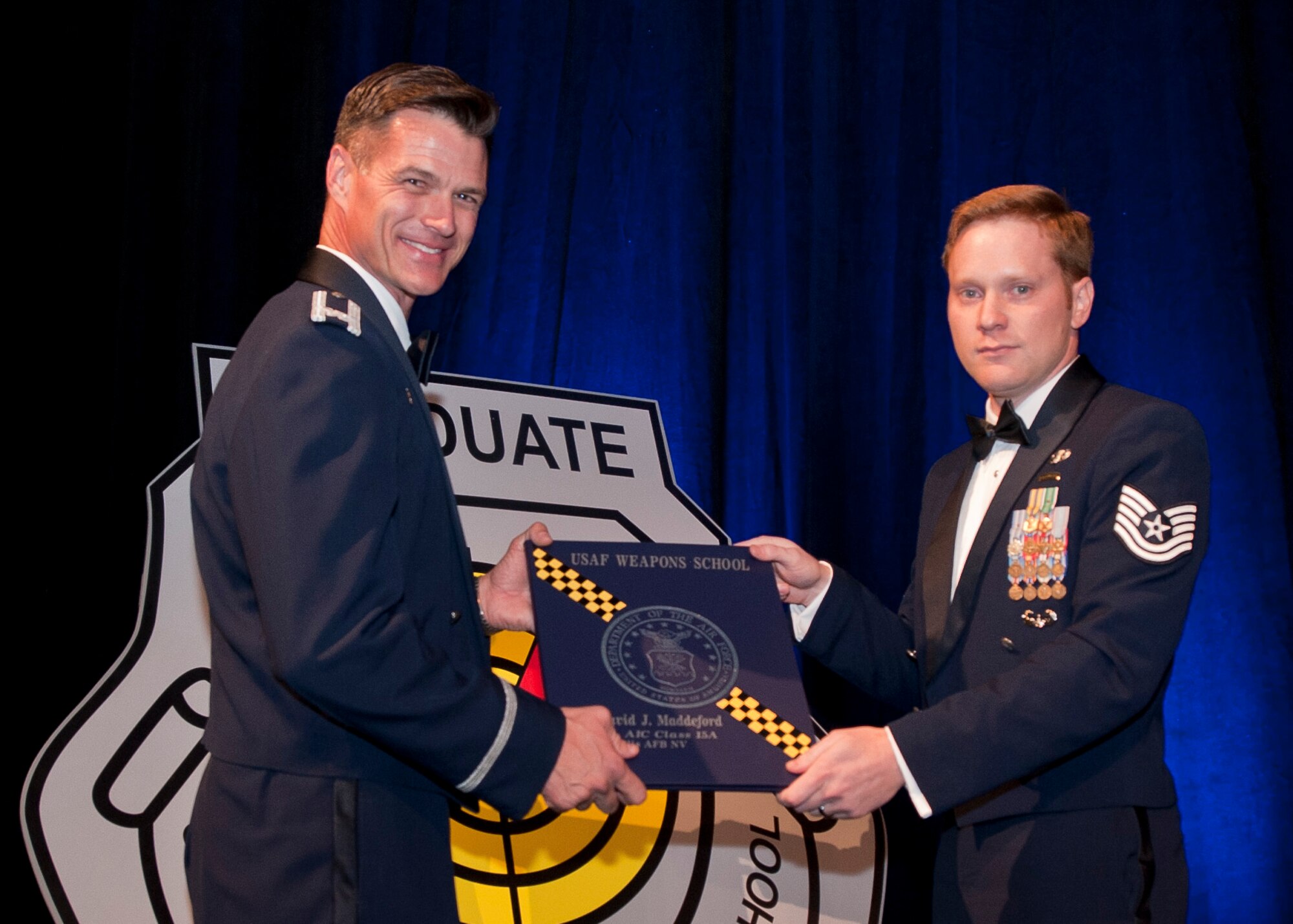 U.S. Air Force Tech. Sgt. David Maddeford receives his Weapons School diploma from Col. Michael Drowley, Commandant, for USAF Weapons School, during a ceremony held June 27, 2015, in Las Vegas, Nev. Maddeford, a Joint Terminal Attack Controller (JTAC) with the 118th Air Support Operations Squadron, New London, N.C., was also one of five enlisted JTACs who made history by being the first enlisted graduates awarded the coveted graduate patch and enter into an elite group of “patch wearer” brethren. (U.S. Air Force photo by Senior Airman Joshua Kleinholz/Released)