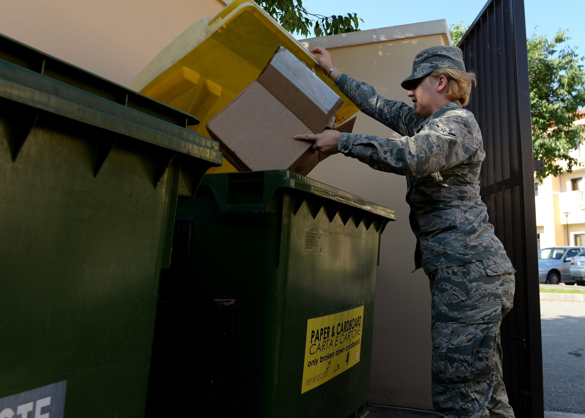U.S. Air Force Airman McKenna Mather, 31st Aerospace Medical Squadron, recycles cardboard in the proper `recycling container, June 30, 2105, at Aviano Air Base, Italy. There are approximately 600 containers at more than 100 collection points throughout Aviano for gathering recyclable items. 