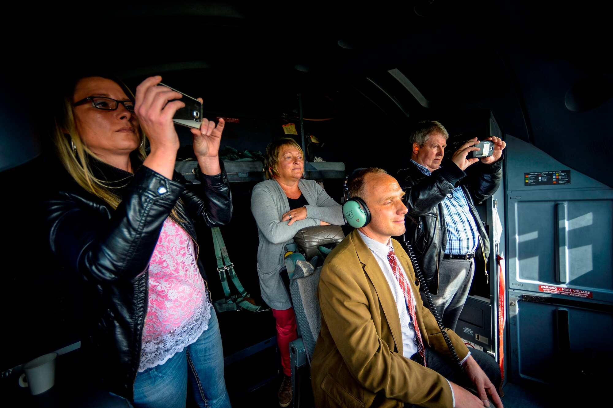 Local nationals look out the window and take photos from inside the cockpit of a C-130J Super Hercules during an orientation flight for German local nationals June 29, 2015, at Ramstein Air Base, Germany. The flight was designed to give German members a better understanding of what Airmen at Ramstein do, and give them an appreciation of how much their work affects the mission. (U.S. Air Force photo/Senior Airman Nicole Sikorski)