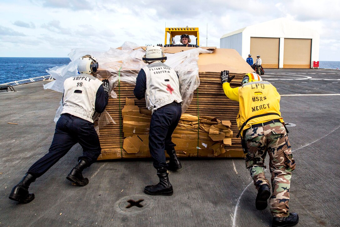U.S. sailors push a pallet of tri-wall containers onto a forklift on the flight deck of the hospital ship USNS Mercy during an underway replenishment in the Solomon Sea, June 26, 2015. The Mercy was participating in Pacific Partnership 2015.
