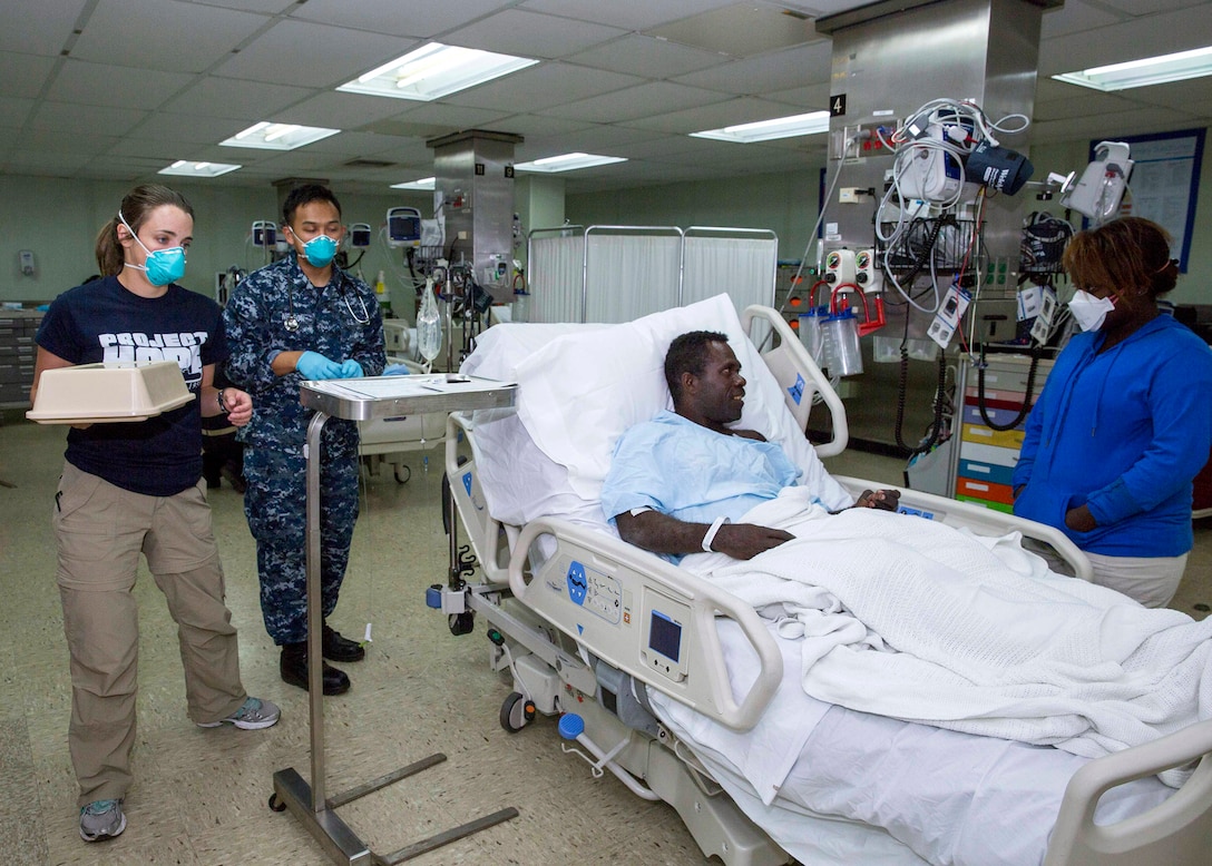 A U.S. sailor and a Project Hope volunteer look after a patient aboard the hospital ship USNS Mercy after a patient transport mission in Arawa, Papua New Guinea, June 30, 2015.