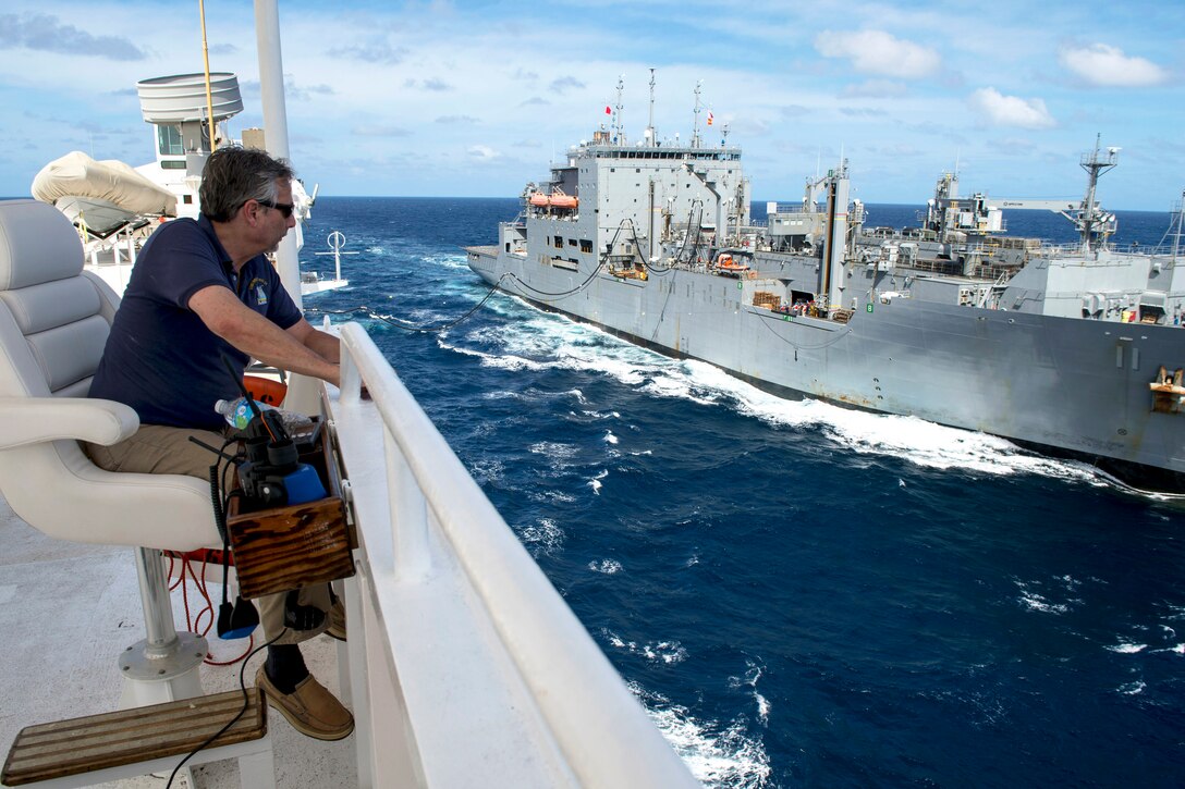 U.S. Navy Capt. Thomas Giudice, the master of the hospital ship USNS Mercy, watches as the USNS Washington Chambers transfers fuel during an underway replenishment in the Solomon Sea, June 26, 2015. The Mercy was participating in Pacific Partnership 2015.
