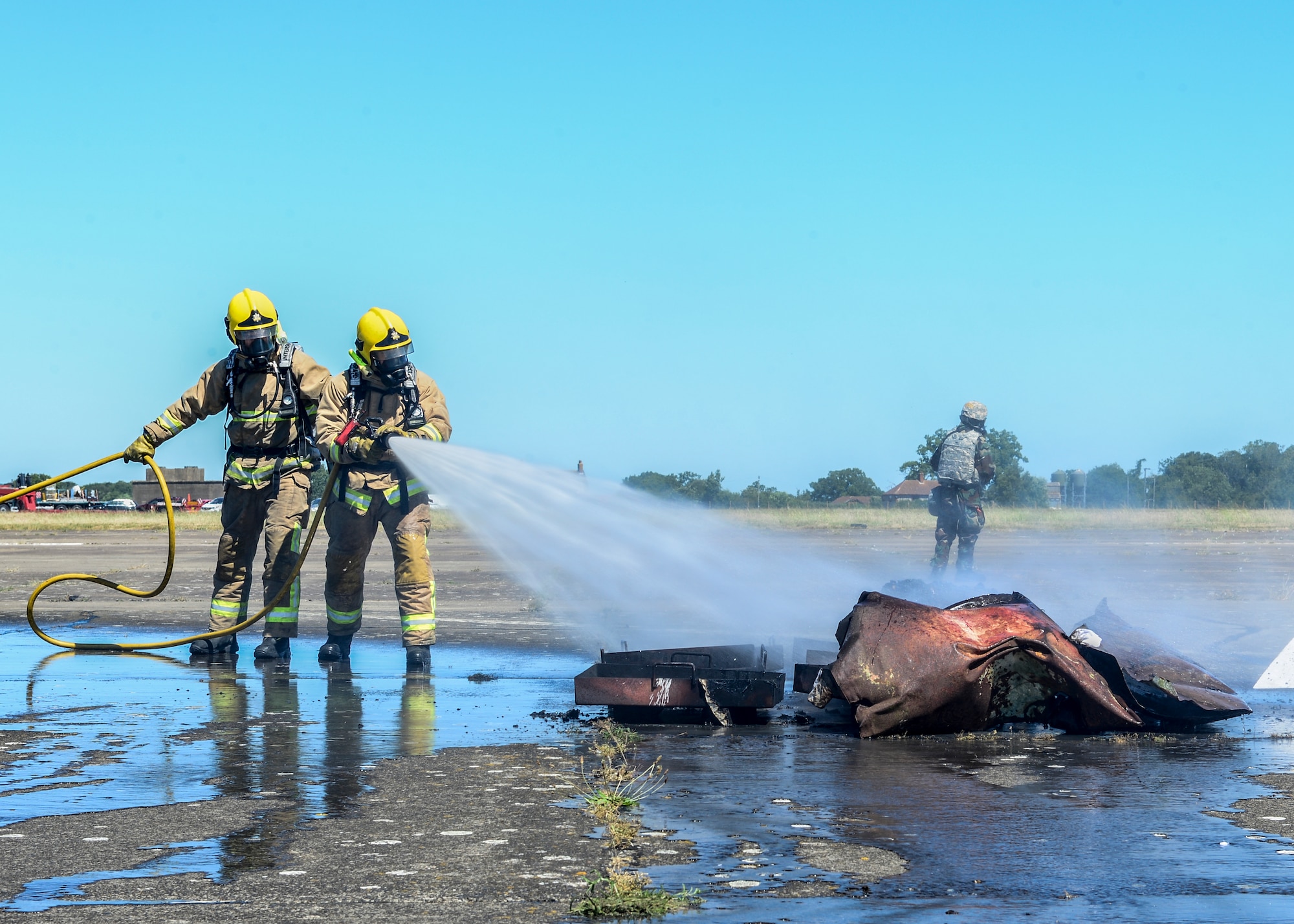 Suffolk Fire Department firefighters extinguish flames on aircraft debris during exercise Diamond Dragon at Royal Air Force Honnington, England, June 30, 2015. Diamond Dragon is a three-day, joint forces response exercise that readies members of the U.K. Ministry of Defense, emergency response agencies and the U.S. Air Force for incidents that require help from both nations. (U.S. Air Force photo by Senior Airman Nigel Sandridge/Released)
