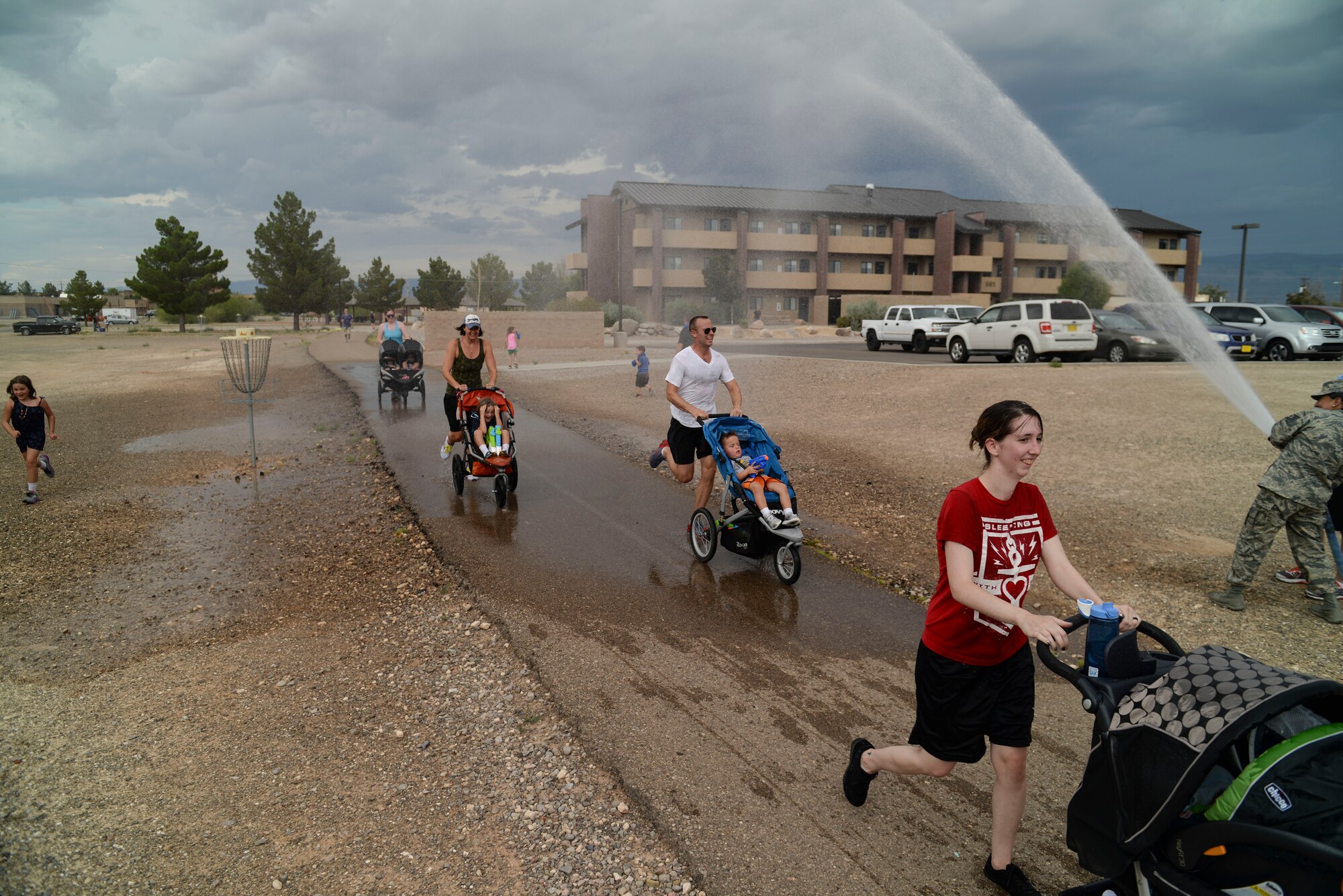 Racers are sprayed by Team Holloman members during the water fun run at Freedom Fest Independence Day celebration at Holloman Air Force Base, N.M., July 2, 2015. Freedom Fest took place in the Domenici Fitness and Sports Center parking lot and included carnival games, rides, and live music for Airmen and their families. (U.S. Air Force photo by Senior Airman Chase Cannon/Released)