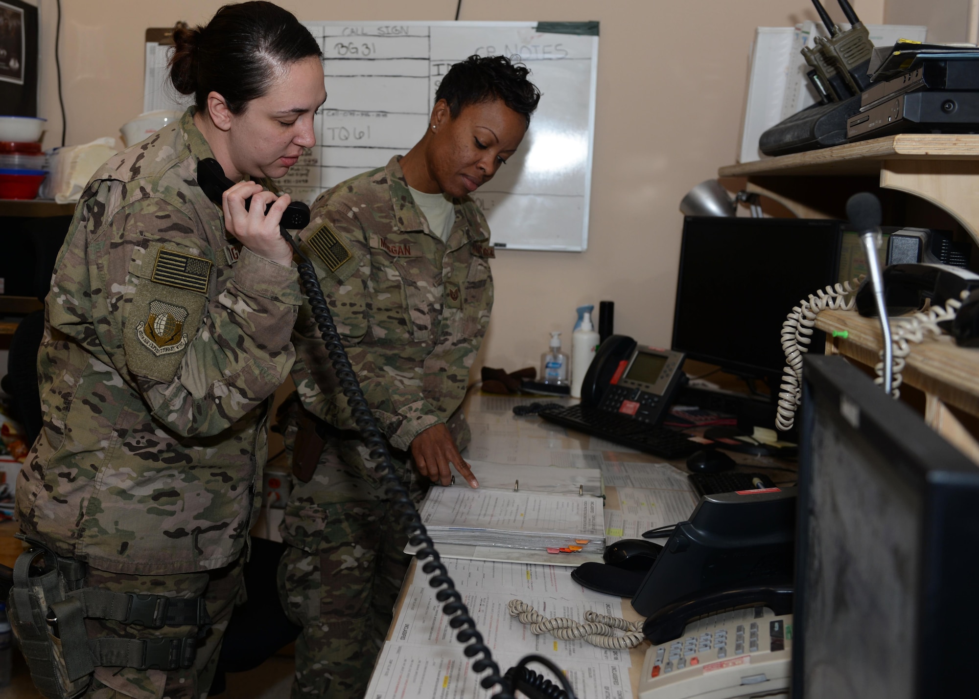 U.S. Air Force Tech. Sgt. Samantha Morgan, 455th Air Expeditionary Wing Command Post non-commissioned officer in charge of operations and Staff Sgt. Sidra Bright, 455th AEW non-commissioned officer in charge of command post systems, assist each other in disseminating mission critical information to wing leadership July 6, 2015, at Bagram Airfield, Afghanistan. The BAF Command Post team is responsible for initiating wing recalls, relaying weather and inbound attack notifications to the base as well as work with aircrews and other various agencies in keeping the base abreast on important information. (U.S. Air Force photo by Senior Airman Cierra Presentado/Released)