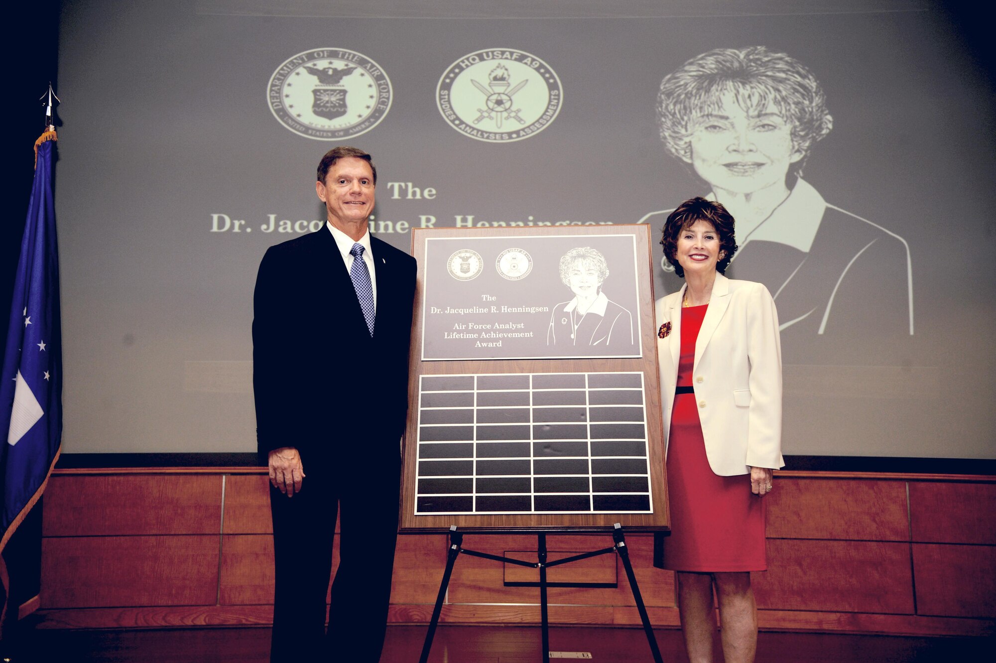 Kevin E. Williams, Director, Air Force Studies, Analyses and Assessments, and Dr. Jacqueline R. Henningsen unveil the Air Force Analyst Lifetime Achievement Award renamed after Dr. Henningsen at the Mark Center, Arlington, Va., June 25, 2015. (U.S. Air force photo/Staff Sgt. Whitney Stanfield)
