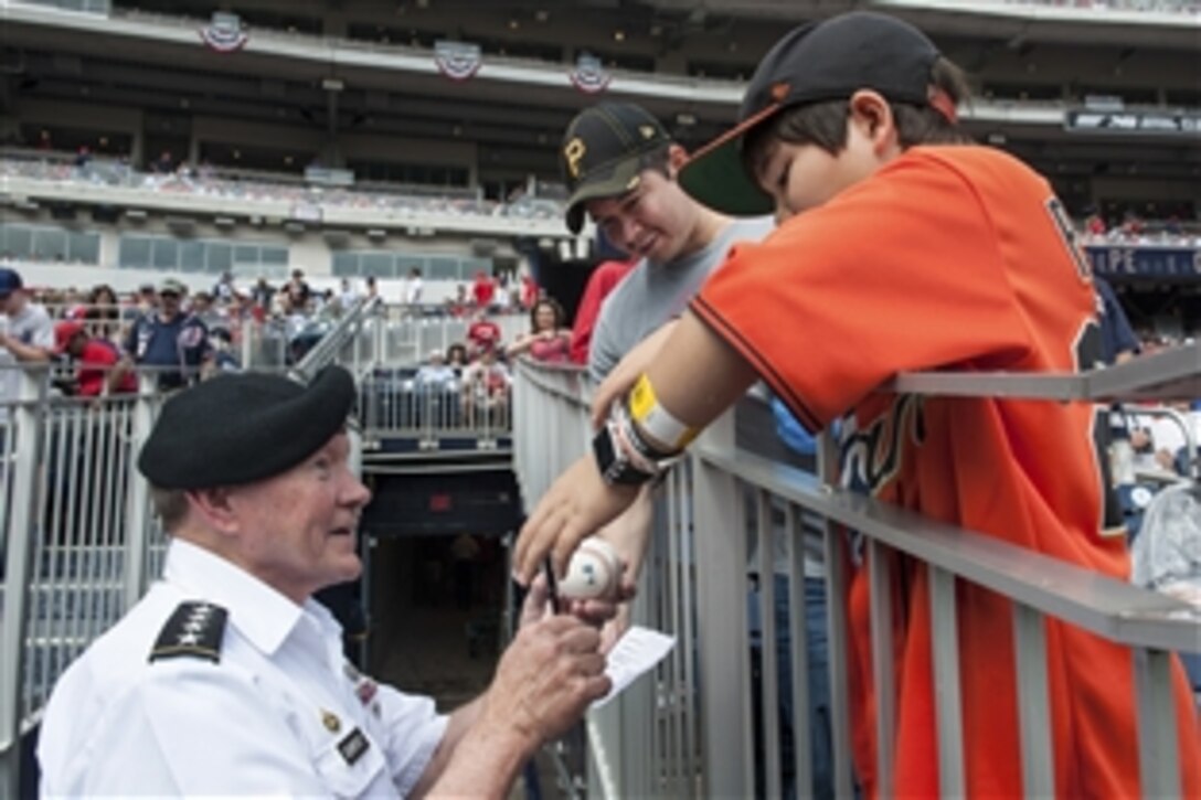 Army Gen. Martin E. Dempsey, chairman of the Joint Chiefs of Staff, signs a baseball for a child during the game between the Washington Nationals and San Fransisco Giants at Nationals Park in Washington, D.C., July, 4, 2015. 
