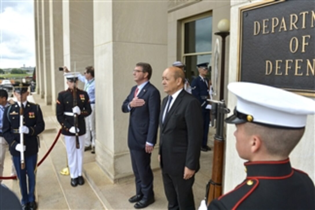 U.S. Defense Secretary Ash Carter, left, and French Defense Minister Jean-Yves Le Drian stand as the U.S. and French national anthems play during an honor cordon before the two leaders met to discuss matters of mutual importance at the Pentagon, July 6, 2015.