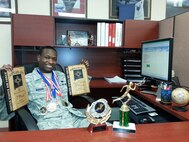 Staff Sgt. Dominic Kosgei, NCO in charge of traffic management for the 377th Logistics Readiness Squadron, displays his numerous running awards.  Kosgei, who was the Air Force recipient for the 2015 American Legion Spirit of Service Award, has never lost in a Tiger Run at Kirtland. (Courtesy photo)