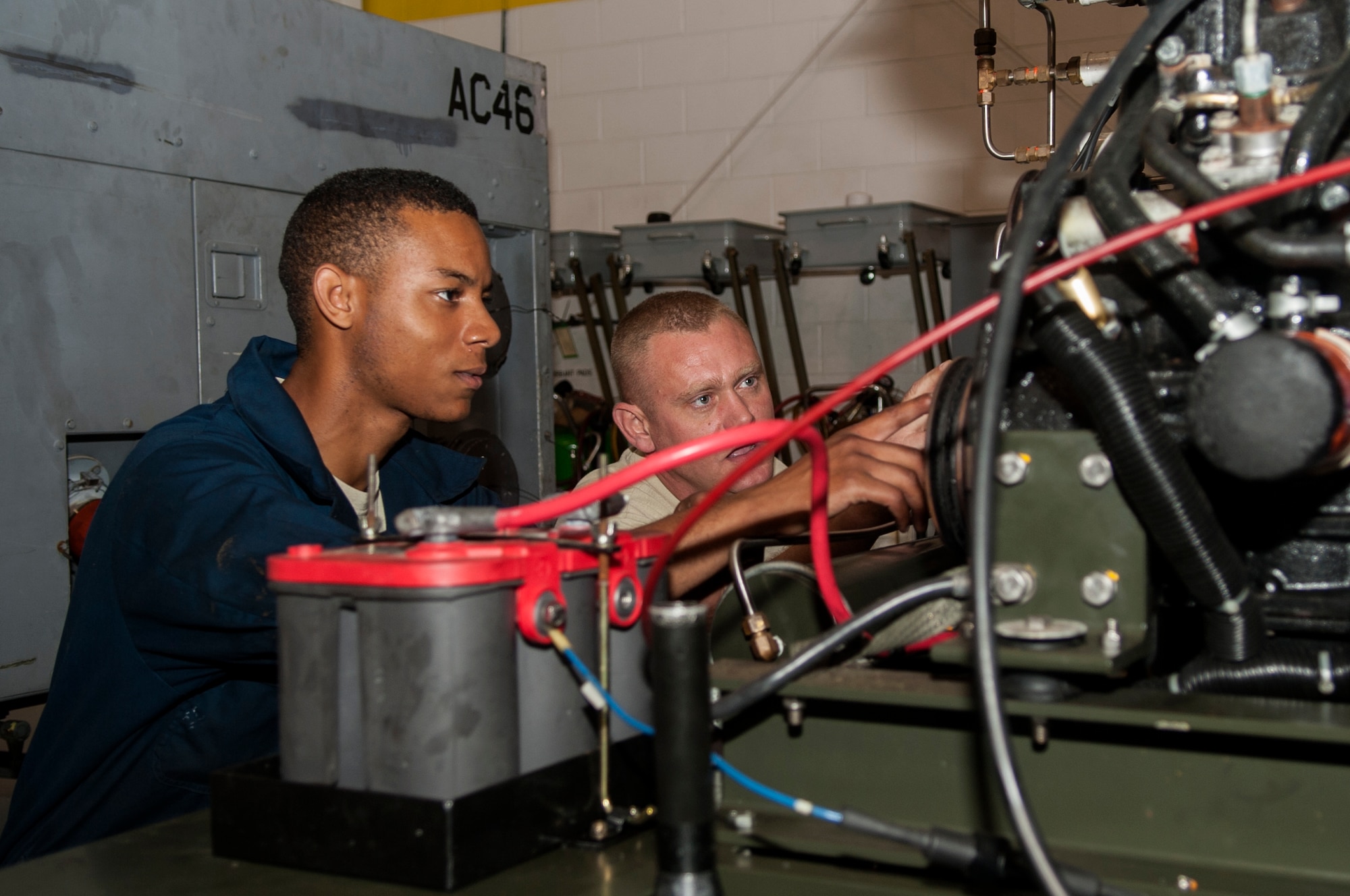 Senior Airman Brandon Martin (left), 4th Equipment Maintenance Squadron aerospace ground equipment technician, follows along with Staff Sgt. Nicholas Burgess, 4th EMS AGE assistant floor lead, as he instructs him on a piece of equipment, June 25, 2015, at Seymour Johnson Air Force Base, North Carolina. AGE Airmen attend six months of technical school at Shepperd Air Force Base, Texas, to learn the basics of their career field. (U.S. Air Force photo/Airman Shawna L. Keyes)