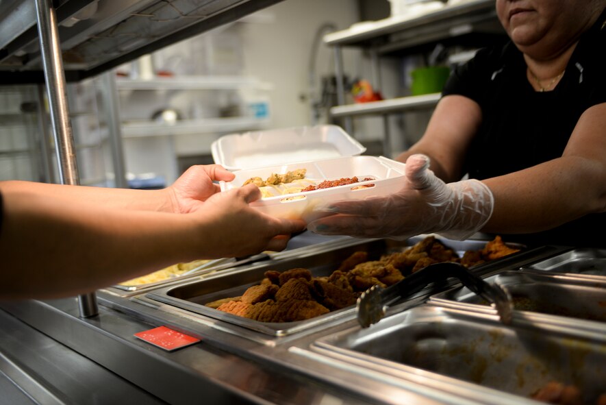 Cany Del Valle, 23d Force Support Squadron Turn N’ Burn Flight Kitchen food service worker, hands a meal to a customer June 30, 2015, at Moody Air Force Base, Ga. The flight kitchen is located between the 23d Security Forces Squadron armory and the Fire Department. (U.S. Air Force photo by Senior Airman Sandra Marrero/Released)