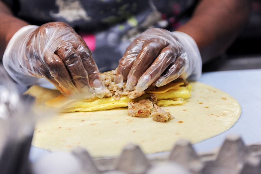 Sylvia Ryan, 23d Force Support Squadron Turn N’ Burn Flight Kitchen food service worker, prepares breakfast for a customer July 1, 2015, at Moody Air Force Base, Ga. Airmen can choose from a variety of ingredients to add to their meals. (U.S. Air Force photo by Senior Airman Sandra Marrero/Released)