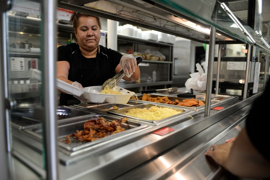 Candy Del Valle, 23d Force Support Squadron Turn N’ Burn Flight Kitchen food service worker, serves lunch June 30, 2015, at Moody Air Force Base, Ga. The flight kitchen is designed to help Airmen on the flightline get a quick nutritious meal, but is open to all of Team Moody. (U.S. Air Force photo by Senior Airman Sandra Marrero/Released)