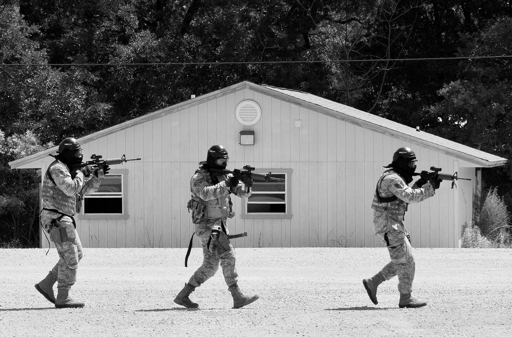 A team of 96th Security Forces Squadron Airmen move between buildings during a shoot, move and communicate drill in June at Eglin Air Force Base, Fla.  The mandatory training requirement is in addition to annual weapons qualification training.  The exercise consists of Airmen firing simmunition ammo while advancing toward, away from and to the side of a target.  This is followed by a building sweep and clear drill.  The Defenders perform the highly kinetic training at Eglin’s Base Tango range.  The range was previously used for security forces pre-deployment training.  (U.S. Air Force photo/Samuel King Jr.)