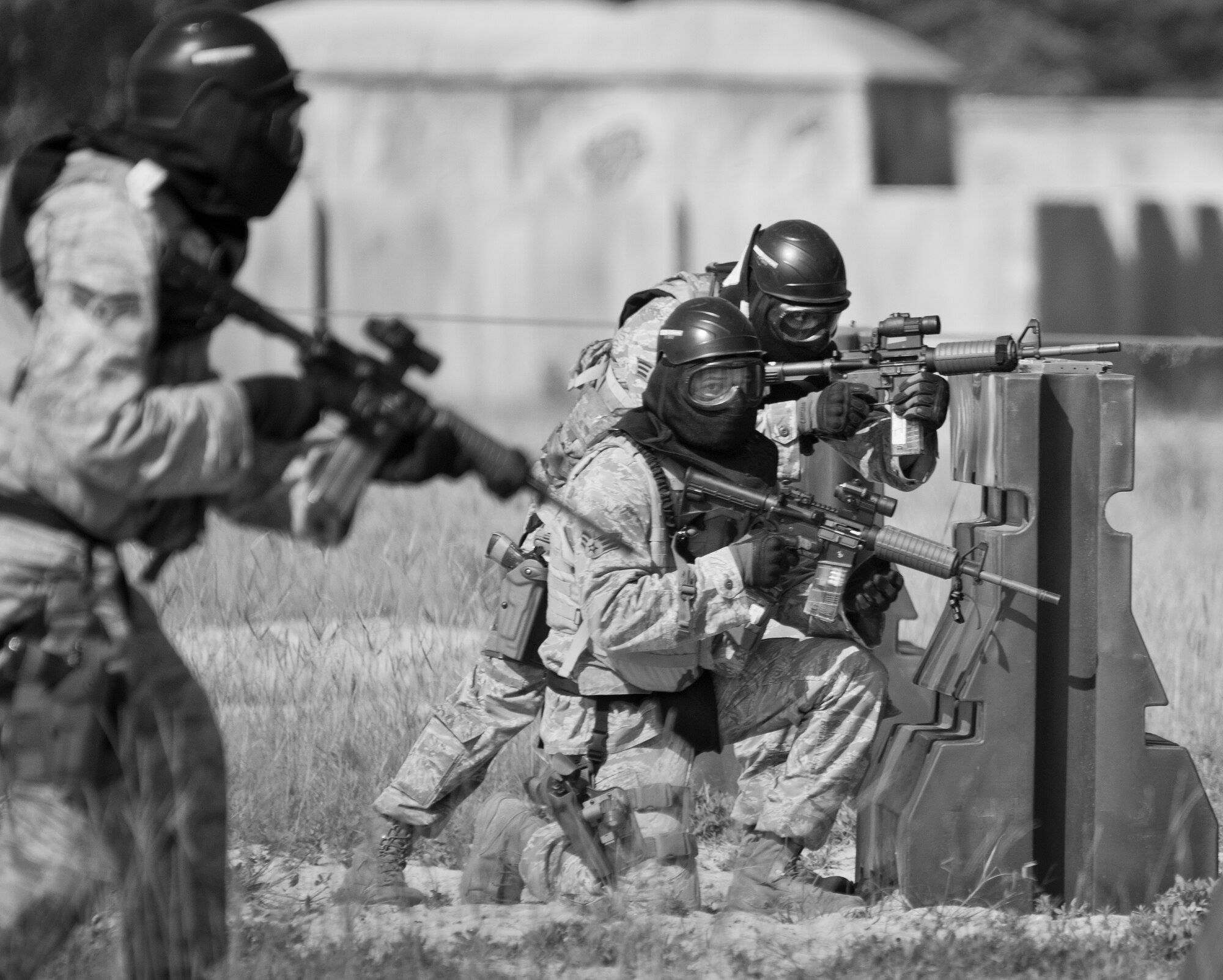 A pair of 96th Security Forces Squadron Airmen covers two more defenders as they advance forward during a shoot, move and communicate drill in June at Eglin Air Force Base, Fla.  The mandatory training requirement is in addition to annual weapons qualification training.  The exercise consists of Airmen firing simmunition ammo while advancing toward, away from and to the side of a target.  This is followed by a building sweep and clear drill.  The Defenders perform the highly kinetic training at Eglin’s Base Tango range.  The range was previously used for security forces pre-deployment training.  (U.S. Air Force photo/Samuel King Jr.)