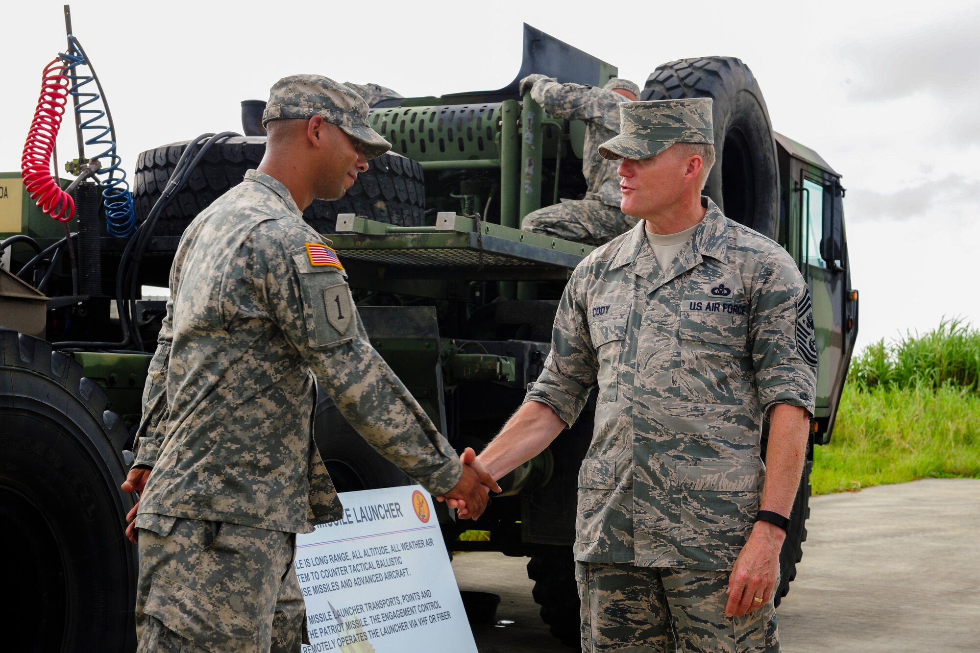 Chief Master Sgt. of the Air Force James Cody presents a coin to U.S. Army Sgt. Henry Harley, 1st Battalion, 1st Air Defense Artillery senior mechanic, July 6, 2015, at Kadena Air Base, Japan. While on Kadena, Cody spoke face-to-face with enlisted service members as he visited the different units and personnel that make up Team Kadena. (U.S. Air Force photo by Airman 1st Class John Linzmeier)