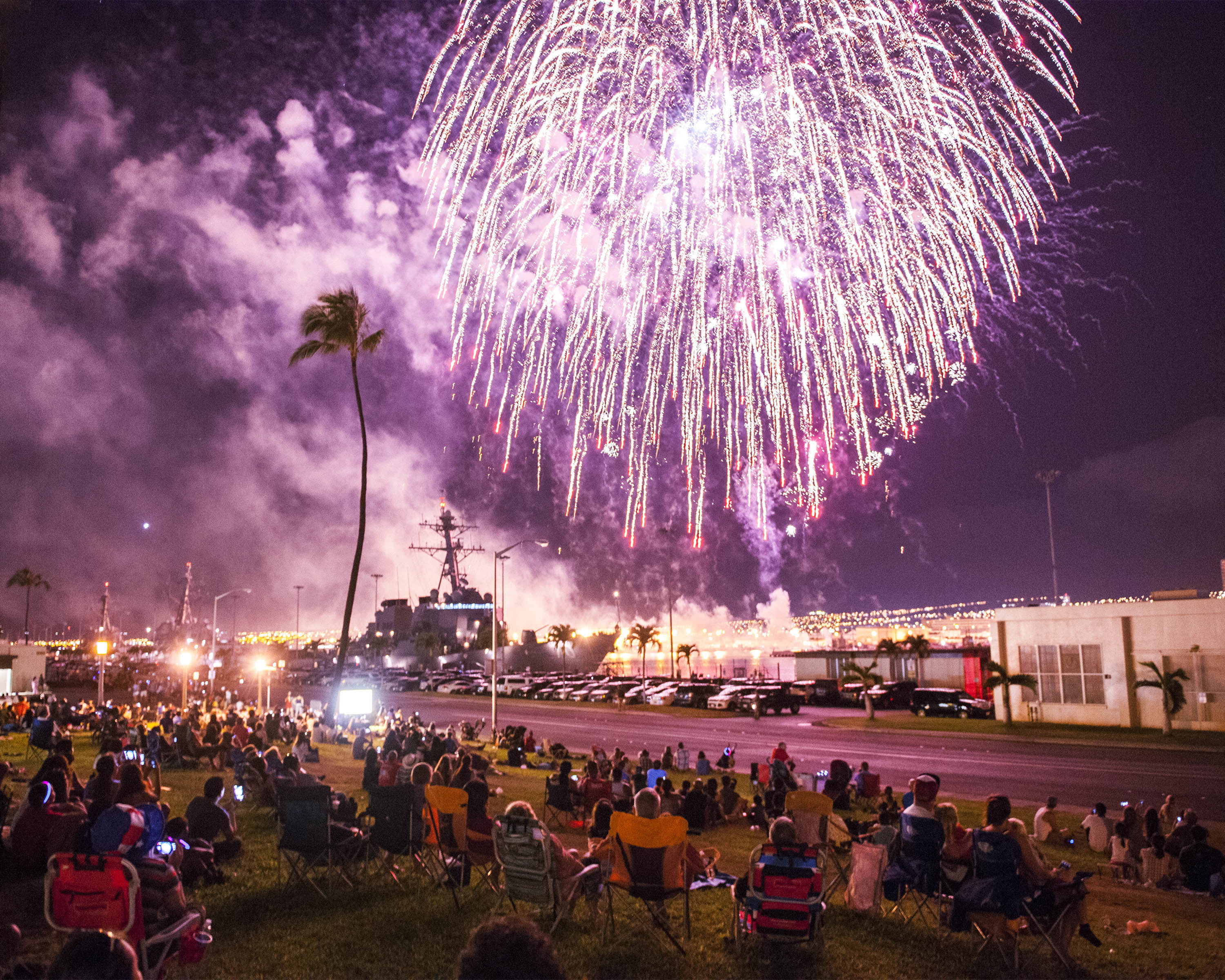 Service members and their families watch a fireworks display during a
