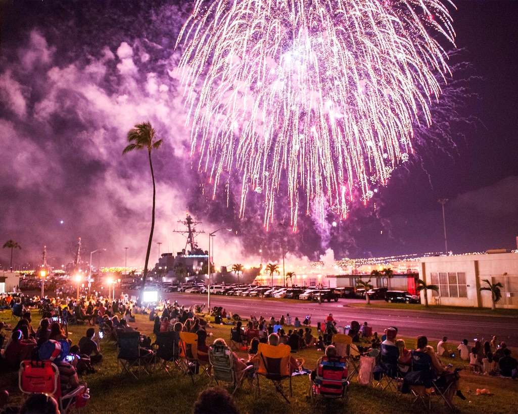 Service members and their families watch a fireworks display during a