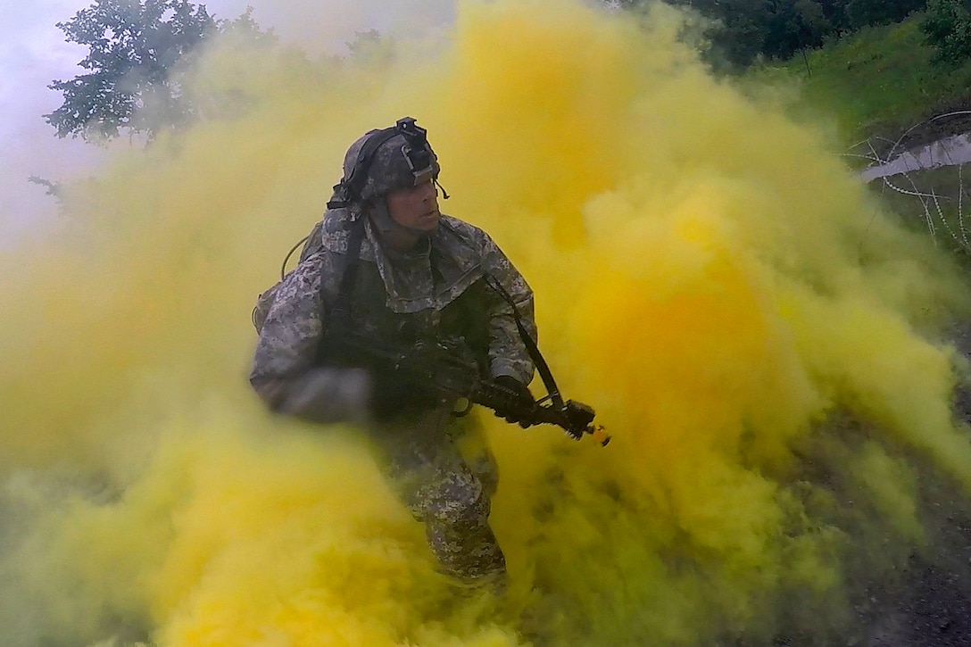 A soldier runs through smoke to return to cover after placing a ...