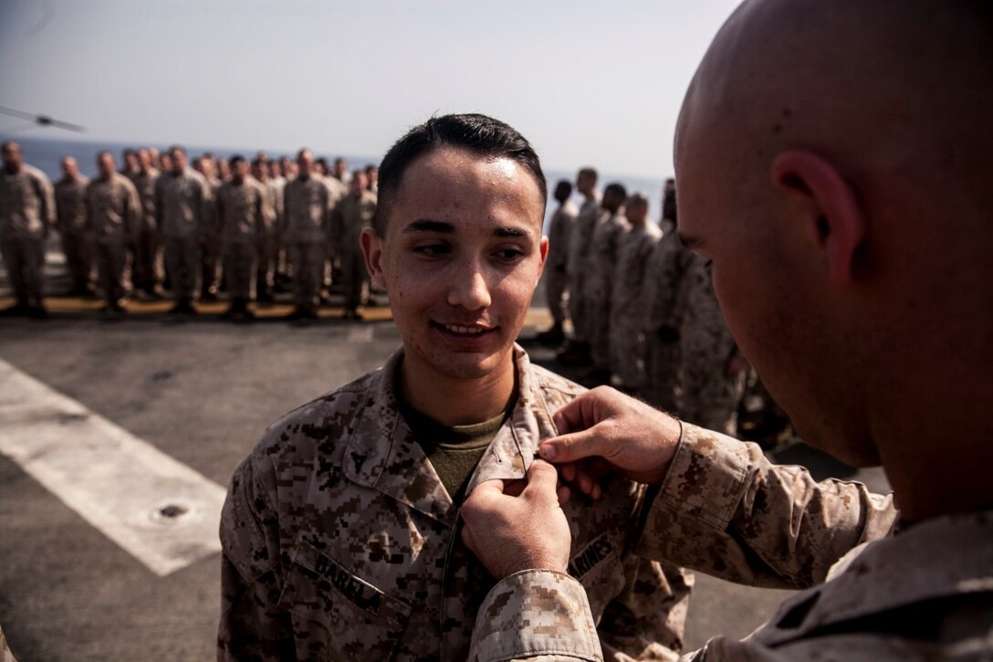 U.S. Marine Cpl. Robert Barela III is pinned by his fellow Marines from the 15th Marine Expeditionary Unit during a promotion ceremony aboard the amphibious assault ship USS Essex (LHD 2). The 15th MEU is embarked on the Essex Amphibious Ready Group and deployed to maintain regional security in the U.S. 5th Fleet area of operations. (U.S. Marine Corps photo by Cpl. Elize McKelvey/ Released)