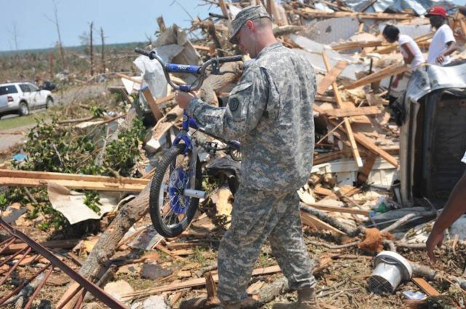 Spc. Robert Boettner, a Soldier form the 31st Chemical Brigade, carries a child's bike from the rubble in the Crescent Ridge area in Tuscaloosa, Ala. April 30, 2011. Many families lost everything during the tornado and little discoveries like this bike that still works helps them to hold on to hope.