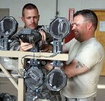 Army Sgt. 1st Class Kevin Dean helps Army Sgt. Mike Main work on a lighting system for a mine resistant ambush protected vehicle at Joint Base Balad, Iraq, April 26, 2011. The Idaho National Guard members are members of the 3rd Battalion, 116th Cavalry Regiment, 77th Sustainment Brigade, 310th Expeditionary Sustainment Personal Security Detachment.