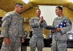 Army Spc. Rafael Santos of the Massachusetts National Guard, right, receives a flag flown over Forward Operating Base Ghazni, Afghanistan, from his platoon leader, Army 1st Lt. Mike Mondello, center, and his platoon sergeant, Army Staff Sgt. Mike Burnes, at a May 5, 2011, celebration welcoming him back to his unit as a new American citizen. The soldiers are security forces members for the provincial reconstruction team in Afghanistan’s Ghazni province.