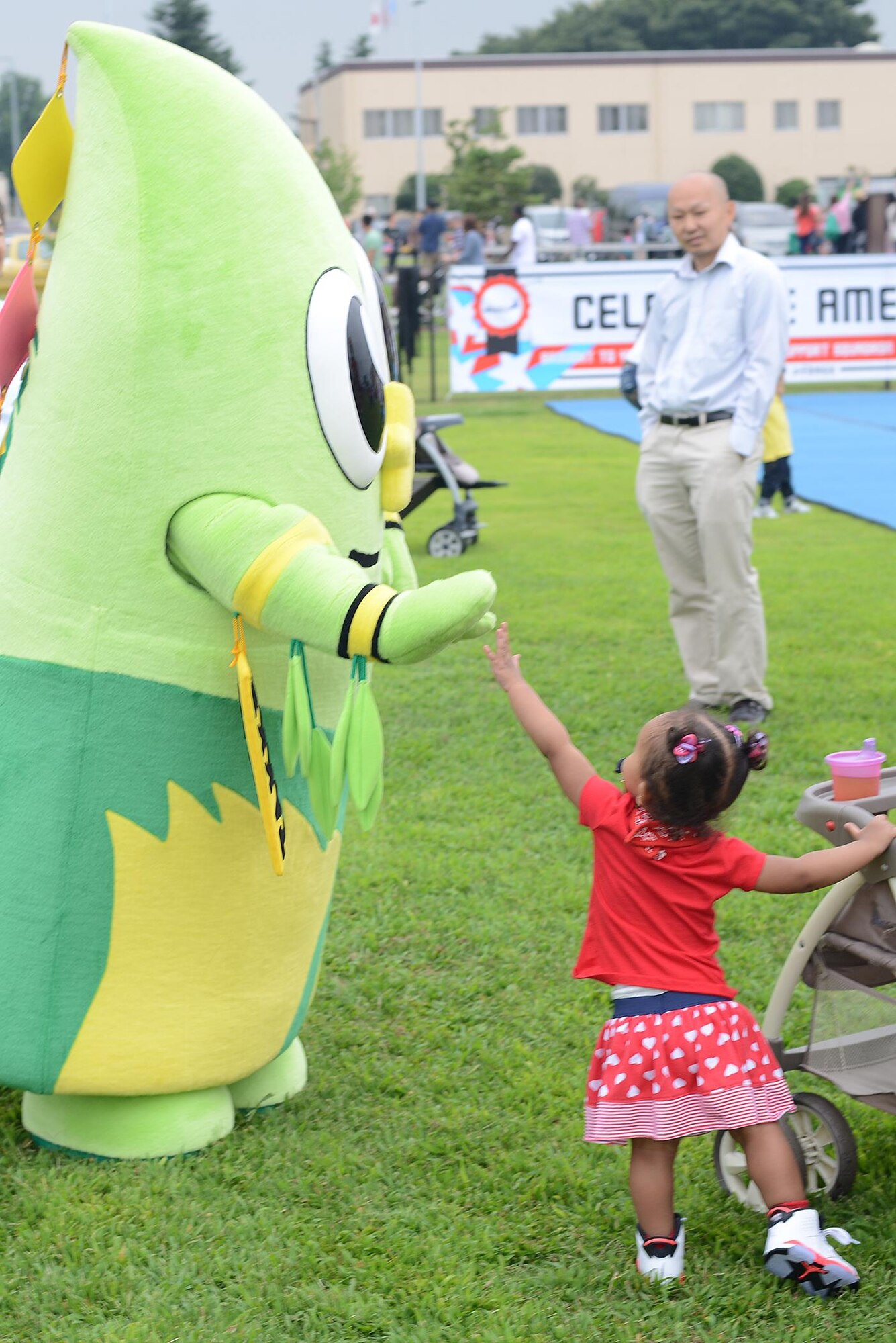 A child high-fives Takke the bamboo, mascot for Fussa city, during the Celebrate America at Yokota Air Base, Japan, July 2, 2015. Yokota borders five municipal cities, each with their own mascot. (U.S. Air Force photo by Airman 1st Class David C. Danford/Released)