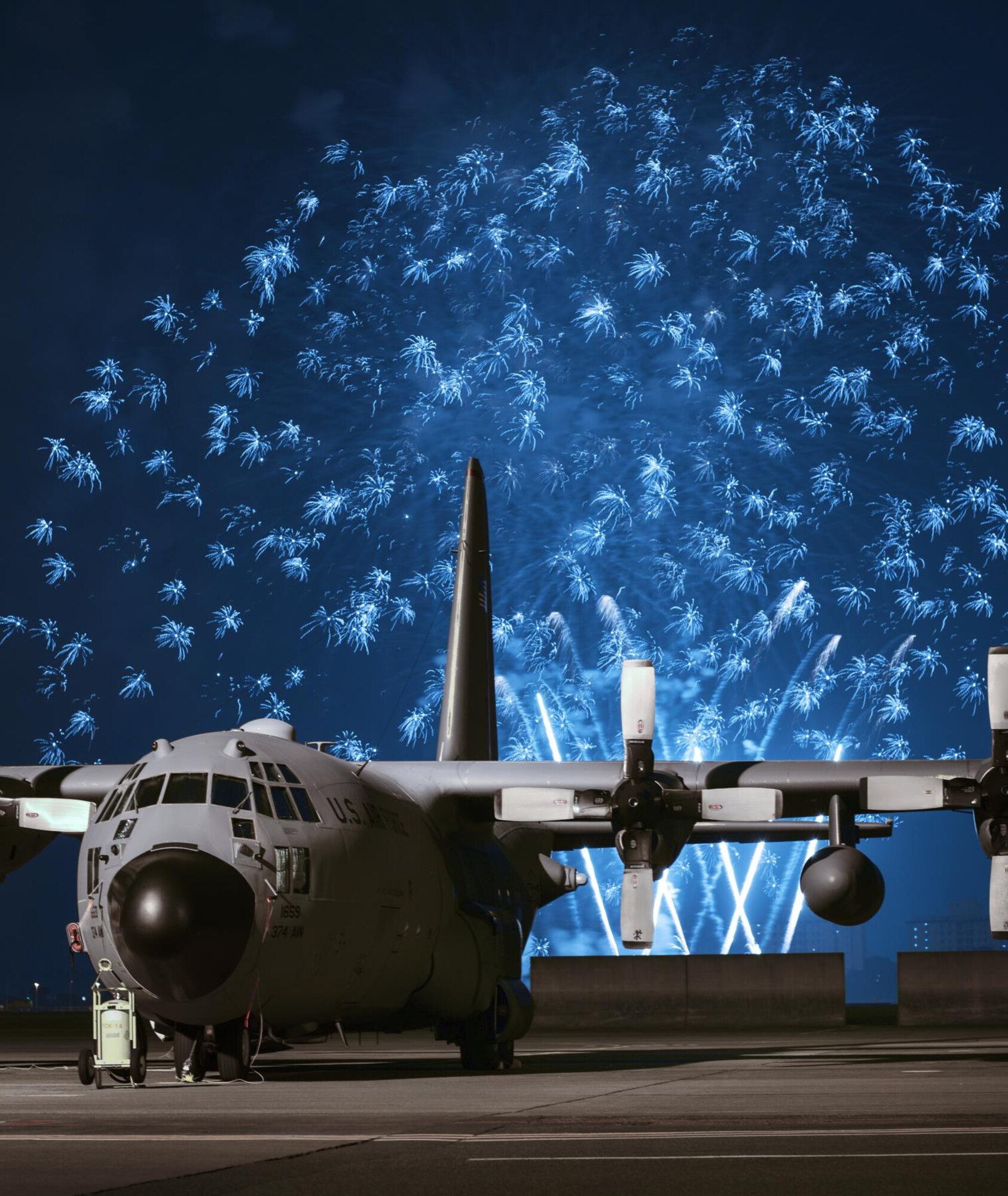 Fireworks explode behind a C-130 Hercules during Celebrate America, July 2, 2015, at Yokota Air Base, Japan. Celebrate America is an annual event that provides military members and their families the opportunity to enjoy games, food and bands before culminating in a fireworks display over the Yokota airfield to celebrate Independence Day. (U.S. Air Force photo by Airman 1st Class Delano Scott/Released)