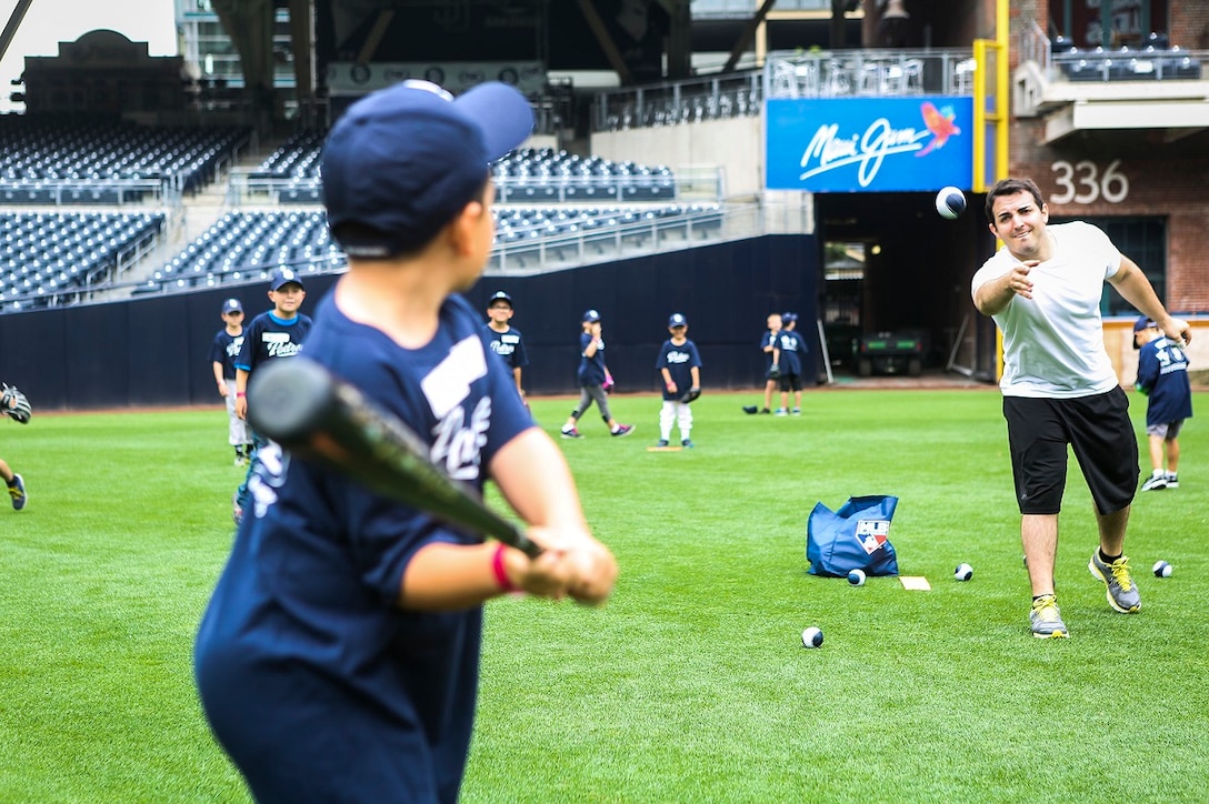 Patrick Coghlan, an intern with the scouting team for the San Diego Padres, tosses a baseball to the son of a servicemember during a Military Kids Baseball Clinic July 2, 2015, in San Diego. Among the children who participated in the event, 50 were dependents of Marines and Sailors currently serving in I Marine Expeditionary Force. The day at the ballpark included batting, pitching and out-fielding drills. The event has taken place three years in a row and is sponsored by the United Services Automobile Association. (Marine Corps Photo by Cpl. Rick Hurtado/Released)