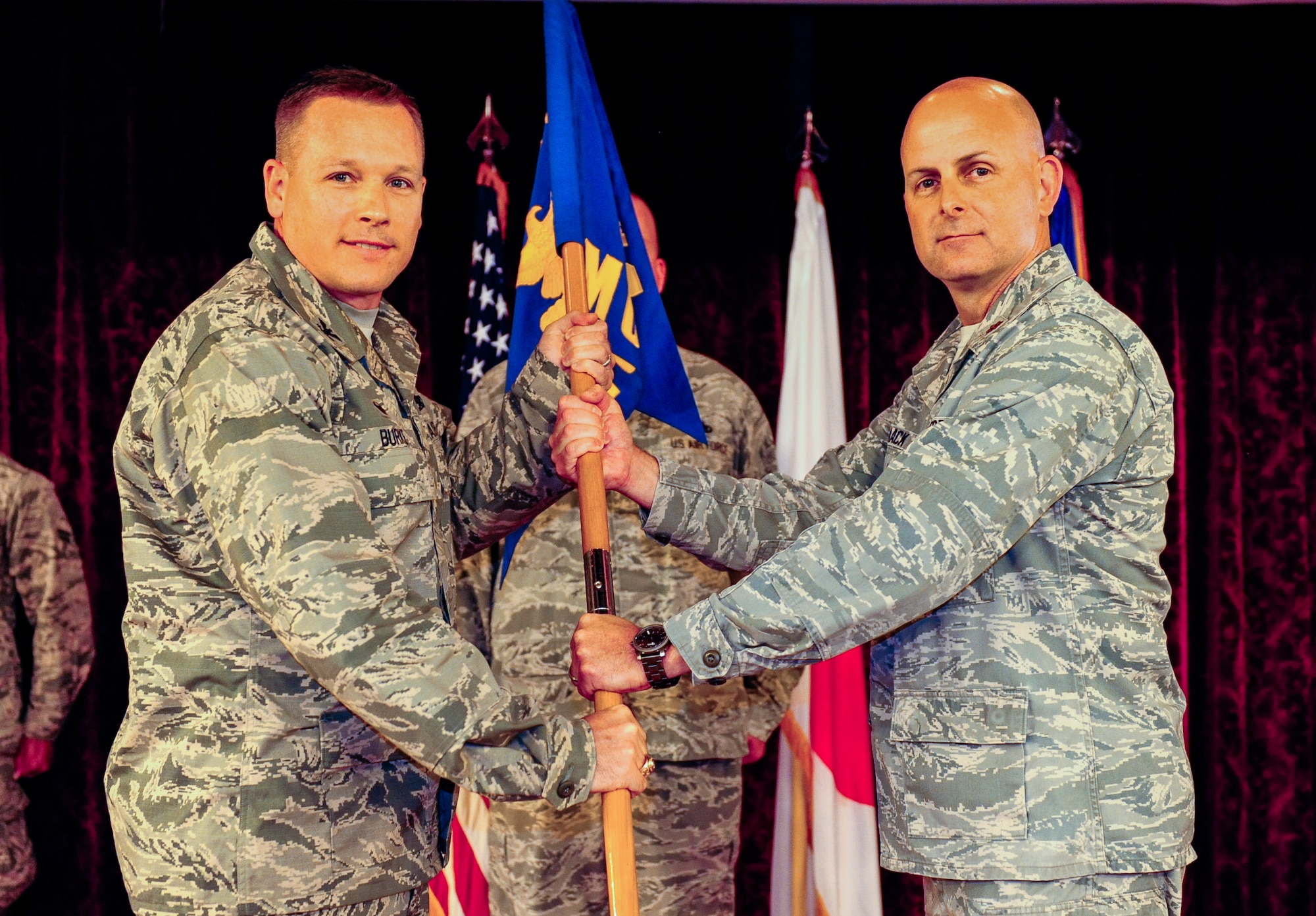 U.S. Air Force Col. Timothy Burke, 18th Maintenance Group commander, passes the 18th Munitions Squadron guidon to Maj. Scott Haack, 18th MUNS commander, during the squadron's change of command ceremony on Kadena Air Base, Japan, July, 2, 2015. The change of command is a traditional military ceremony in which the departing commander assembles his troops for a presentation to the incoming commander. Hack was previously the ammo section chief of Munitions Components Branch, Munitions Sustainment Division, Armament Directorate, at Hill Air Force Base, Utah. (U.S. Air Force by Airman 1st Class John Linzmeier)