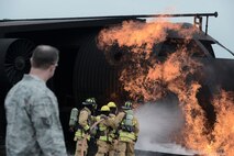 Members with the 374th Civil Engineer Squadron are monitored by Tech. Sgt. Jeremy Hazel during live fire training at Yokota Air Base, Japan, July 7, 2015. Fire protection members practiced extinguishing engine, running fuel and fuselage fires during their monthly training at the fire training pit. Hazel is the 374 CES fire protection assistant chief of operations. (U.S. Air Force photo by Staff Sgt. Cody H. Ramirez/Released)