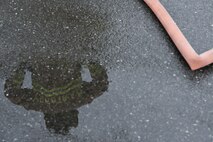 A fire protection member with the 374th Civil Engineer Squadron stands at the fire training pit during live-fire training at Yokota Air Base, Japan, July 7. 2015. More than 20 members participated in the training, allowing them hands-on training with extinguishing engine, running fuel and fuselage fires. (U.S. Air Force photo by Staff Sgt. Cody H. Ramirez/Released)