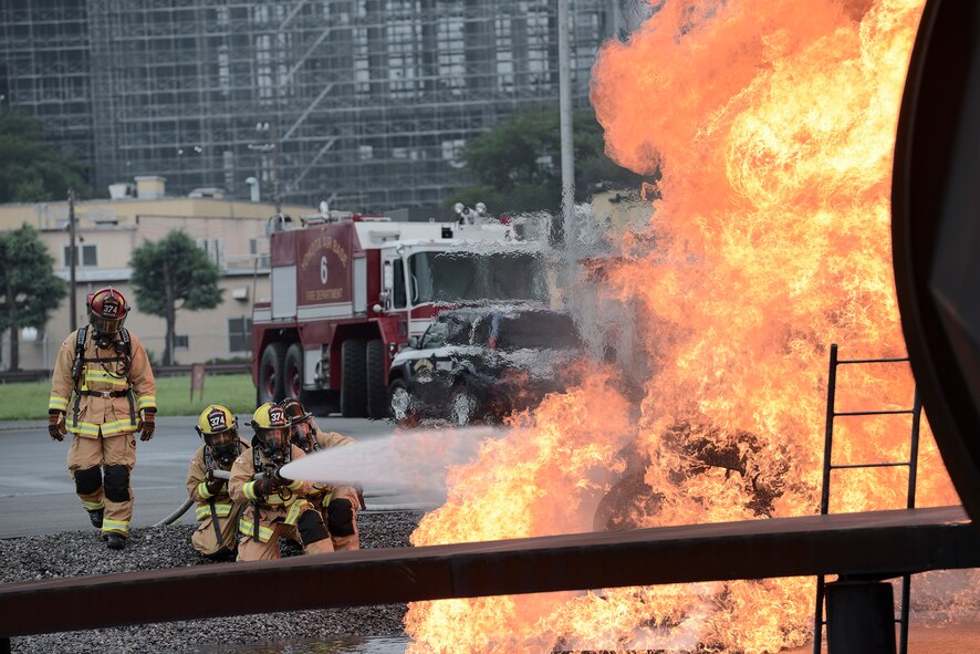 Members with the 374th Civil Engineer Squadron fire protection extinguish a training fire at Yokota Air Base, Japan, July 7, 2015. The fire protection team had many new members and the training allowed them first-hand experience in honing their fire protection skills. (U.S. Air Force photo by Staff Sgt. Cody H. Ramirez/Released)