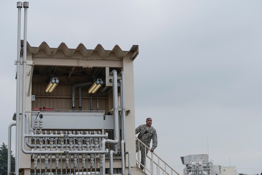 Staff Sgt. Trevor Alexis, 374th Civil Engineer Squadron fire protection NCO in charge of training, runs the gas lines to the fire training pit during live-fire training at Yokota Air Base, Japan, July 7, 2015. The training pit provided mock fires for the teams to extinguishing and the training allowed the members to hone their skills in fire elimination. (U.S. Air Force photo by Staff Sgt. Cody H. Ramirez/Released)