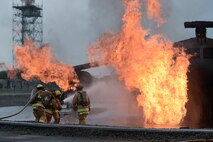 Members with the 374th Civil Engineer Squadron practice fire protection at Yokota Air Base, Japan, July 7, 2015. Fire protection members practiced extinguishing engine, running fuel and fuselage fires during their monthly training at the fire training pit . (U.S. Air Force photo by Staff Sgt. Cody H. Ramirez/Released)