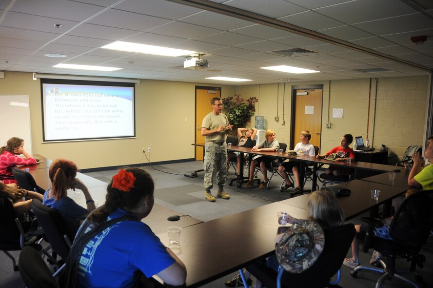 Senior Master Sgt. Carl Schneider, 188th Intelligence Support Squadron cyber systems superintendent, delivers a briefing 188th Wing’s intelligence mission at Ebbing Air National Guard Base, Ark., to students of the Alma School District June 11, 2015. Schneider stressed the importance of critical thinking, problem solving and having a good education. Students of the Alma School District that attend Camp Airedale were able to see the statics of the aircraft the 188th used in previous missions and sat in briefings about the 188th Wing’s current mission before fishing in Ebbing Lake. (U.S. Air National Guard photo by Senior Airman Cody Martin/Released)
