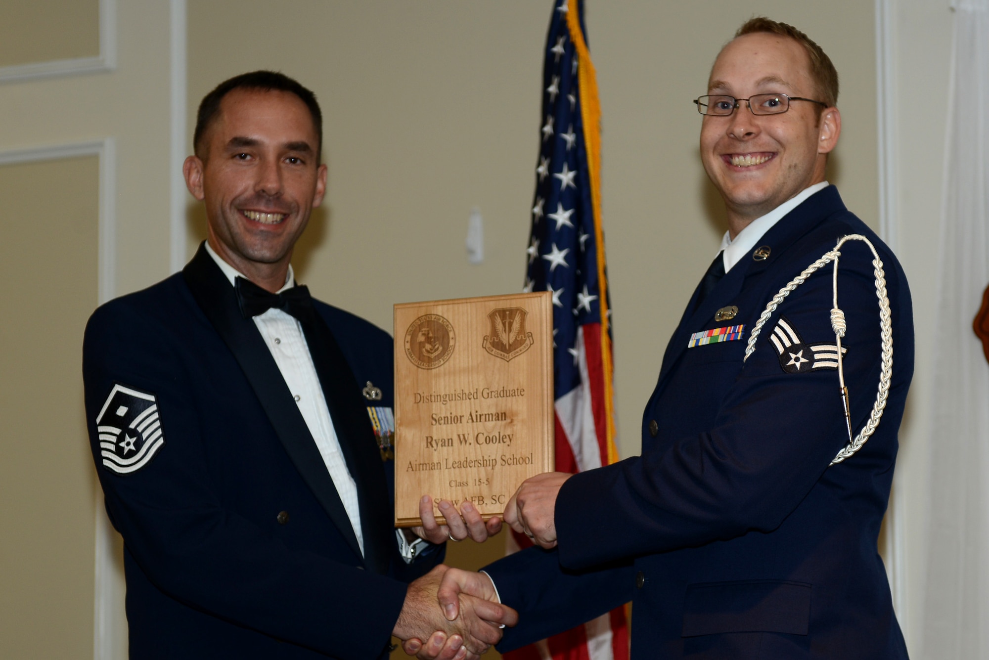 U.S. Air Force Senior Airman Ryan Cooley, 31st Intelligence Squadron, receives a distinguished graduate award for the Senior Master Sgt. David B. Reid Airman Leadership School Class 15-5 from Master Sgt. Robert Finton, 20th Operations Support Squadron first sergeant, at Shaw Air Force Base, S.C., July 2, 2015. The distinguished graduate awards are given to the top 10 percent of the class for total point accumulation. (U.S. Air Force photo by Senior Airman Diana M. Cossaboom/Released)
