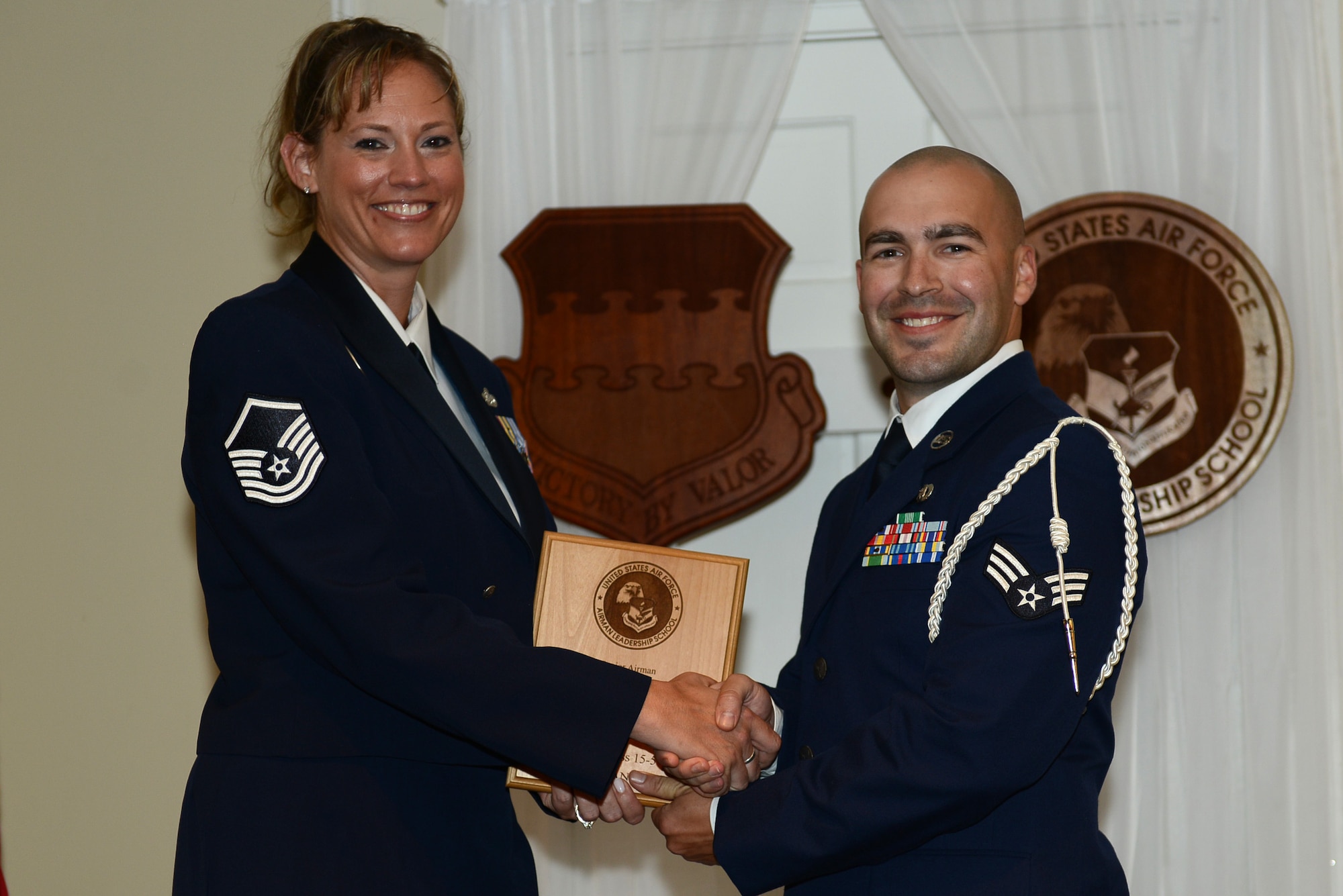 U.S. Air Force Senior Airman Kyle Winston, 15th Air Support Operations Squadron, receives the Senior Master Sgt. David B. Reid Airman Leadership School Commandant Award from Master Sgt. Lindsey Wolf, 20th Force Support Squadron ALS commandant, during the ALS Class 15-5 graduation at Shaw Air Force Base, S.C., July 2, 2015. The commandant’s award is given to the student who most exemplifies professional military qualities as chosen by their peers, primary instructors, and commandant. (U.S. Air Force photo by Senior Airman Diana M. Cossaboom/Released)