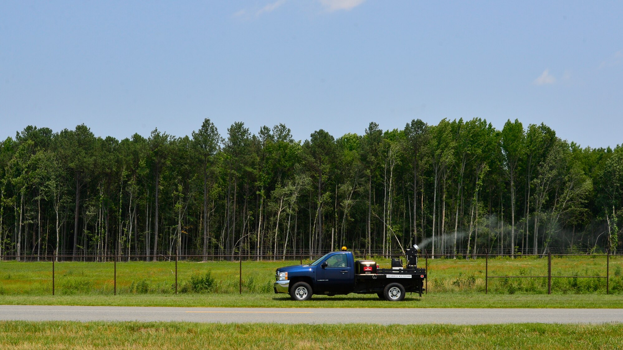 Tech. Sgt. Michael Holmes, 436th Civil Engineer Squadron Pest Management NCO in charge, fogs for mosquitos along the perimeter fence line July 1, 2015, at Dover Air Force Base, Del. Holmes is using an ultra-low-volume fogger that puts out less chemicals than traditional mosquito foggers. (U.S. Air Force photo/Airman 1st Class William Johnson)