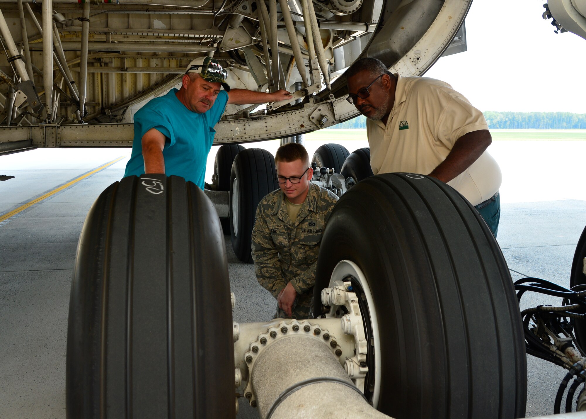 Ken Barnes, 436th Civil Engineer Squadron Pest Management foreman, left, Staff Sgt. Daniel Fink, 436th CES Pest Management supervisor, middle, and Darryl Moore, U.S. Department of Agriculture Plant Health Safe Guarding specialist, right, inspect the landing gear of a C-5M Super Galaxy for Japanese Beetles July 1, 2015, at Dover Air Force Base, Del. The 436th Pest Management shop treats aircraft departing Dover AFB and traveling to one of the nine protected western states against Japanese Beetles as part of a USDA mandated program. (U.S. Air Force photo/Airman 1st Class William Johnson)
