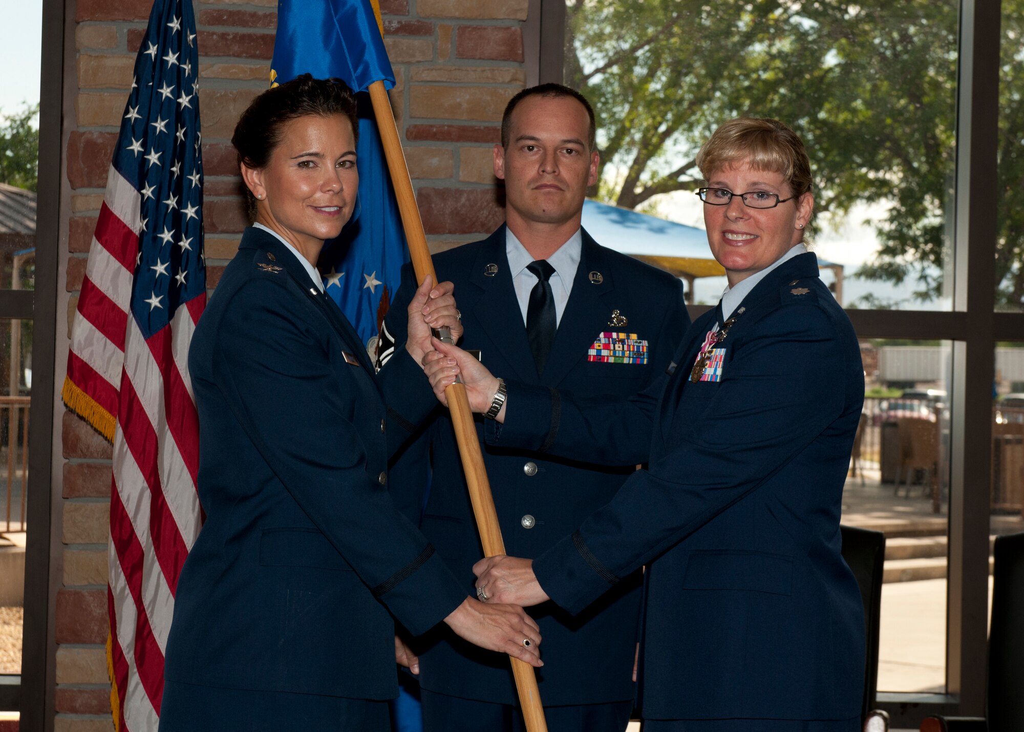 Lt. Col. Kathleen Mackey, the outgoing 49th Medical Support Squadron commander, passes the unit guidon to Col. Leslie A. Knight, the 49th Medical Group commander, during the unit’s change of command ceremony at Holloman Air Force Base, N.M., July 7, 2015. Lt. Col. Elbert Alford assumed command and will lead the 49th MDSS’s 77 active duty and civilian personnel who maintain the operation of all medical support activities, medical readiness items, facility management, and pharmacy operations. (U.S. Air Force photo by Senior Airman Chase Cannon/Released)